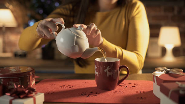 женщина наливая горячий чай в чашку праздника - afternoon tea tea women table стоковые фото и изображения