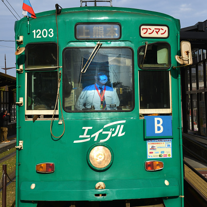 Train attendant with facemask to protect from polution and viruses such as Corona Virus on a sunny day in Tokyo, Japan