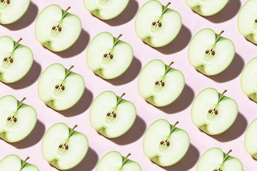 Apple slices in a row on pink background