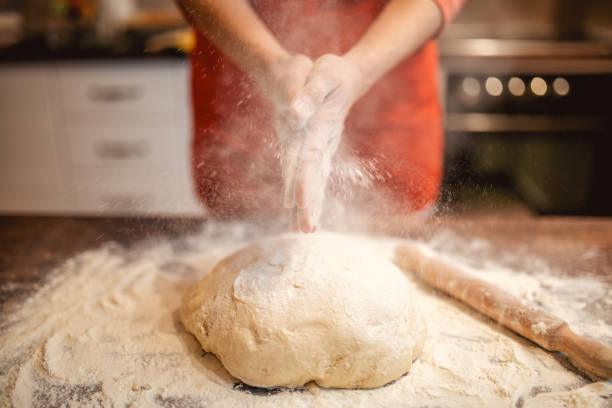 Woman preparing dough for bread Woman preparing and kneading dough for bread and cakes. She wears a red apron and works in her kitchen. She is unrecognizable baking bread photos stock pictures, royalty-free photos & images