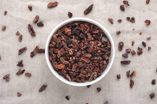 Cacao nibs Cacao nibs in white bowl on table, top view cacao nib stock pictures, royalty-free photos & images