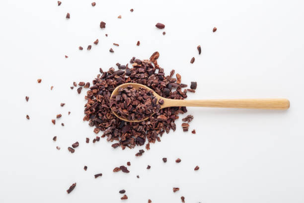 puntas de cacao sobre cuchara de madera, fondo blanco - plumín fotografías e imágenes de stock