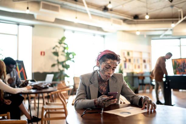 istock Tattooed businesswoman analyzing graphs with mobile phone at work 1210314657