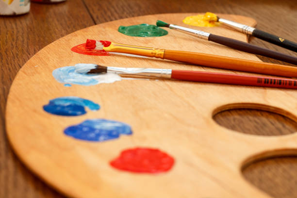 istock Wooden palette with laying on paints and paintbrushes 1210318181