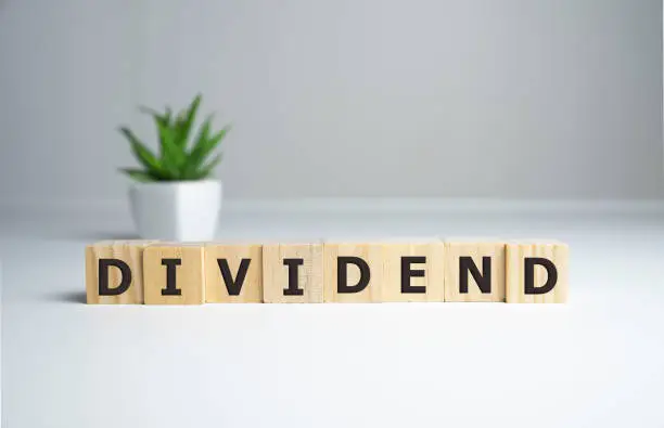 Photo of Text DIVIDEND on cube dice with background, finance concept