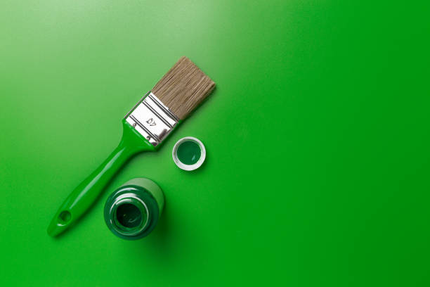 Green paint brush and paint on a green background. Top view