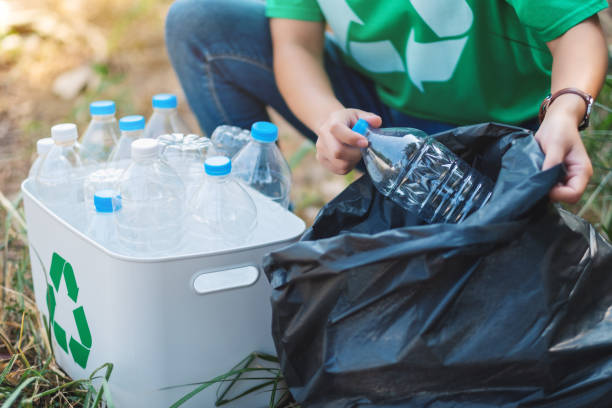 istock A woman picking up garbage plastic bottles into a box and plastic bag for recycling 1210331550