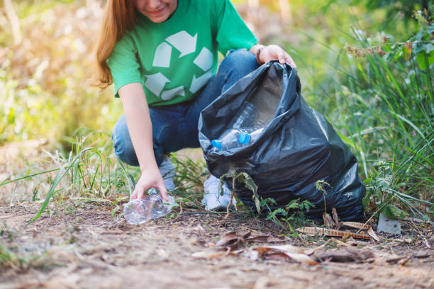 istock a woman picking up garbage plastic bottles into a plastic bag for recycling concept 1210331554