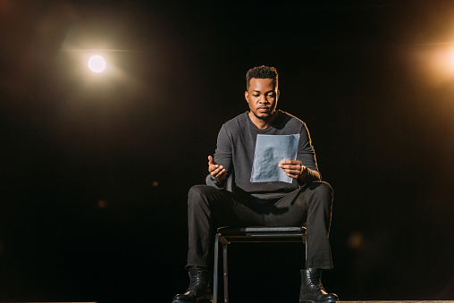 guapo actor afroamericano sosteniendo escenario en el escenario durante el ensayo photo