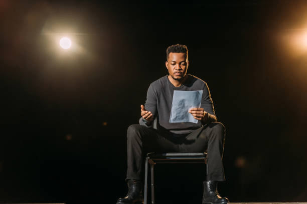 guapo actor afroamericano sosteniendo escenario en el escenario durante el ensayo - guión fotografías e imágenes de stock