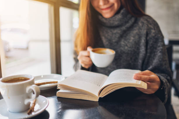 istock a beautiful woman reading a book while drinking coffee in cafe 1210331595