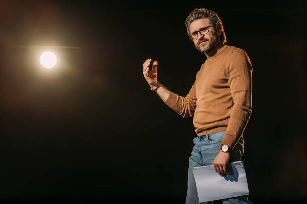 handsome mature actor holding scenario and standing on stage during rehearse handsome mature actor holding scenario and standing on stage during rehearse audition photos stock pictures, royalty-free photos & images
