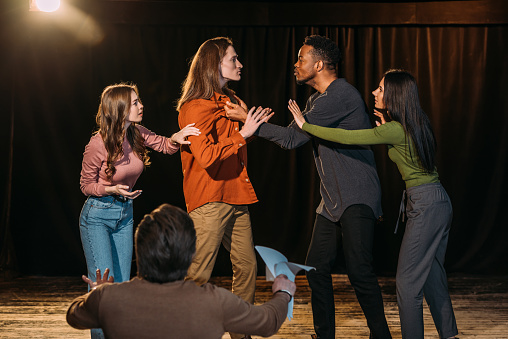 multicultural actors and actresses rehearsing fight on stage in theatre