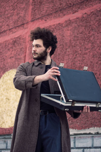 istock Curly man with a beard and a coat opened his suitcase 1210332003