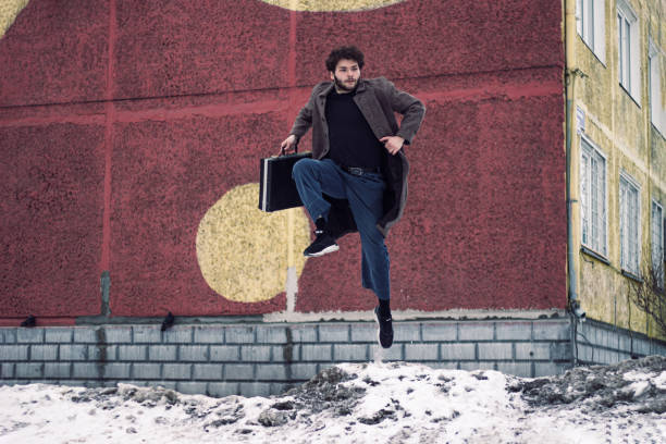 istock Curly man jumping with a suitcase in a coat 1210332008
