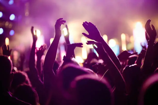 Photo of Cheering crowd with hands in air at music festival