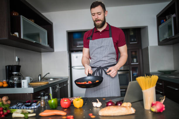 istock Young man cooking vegetables with a pan 1210332696