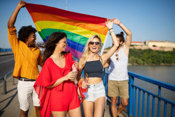 orgulho homossexual, lésbica, comunidade gay em uma parada com as mãos levantadas e a bandeira lgbt - lesbian love sexual issues two people - fotografias e filmes do acervo