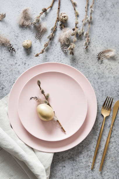 istock Easter table setting with pink and golden decor on grey stone table. Top view. 1210336703