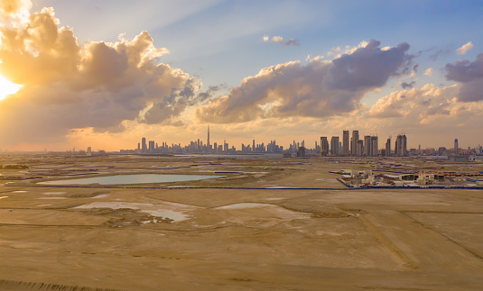Aerial view of Dubai Downtown skyline with desert sand, United Arab Emirates or UAE. Financial district and business area in smart urban city. Skyscraper and high-rise buildings at sunset.