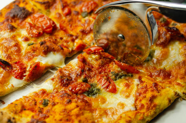 istock Cutting famous Neapolitan pizza based on buffalo mozzarella and tomatoes with a pizza cutter 1210338618