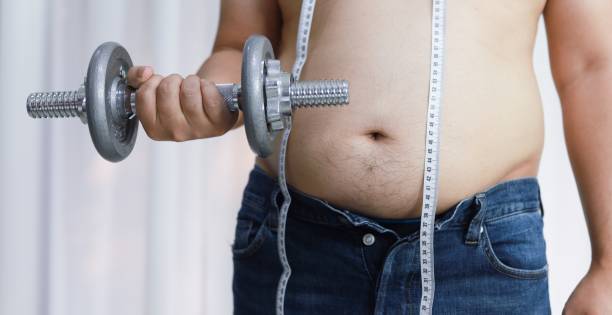istock Overweight man exercising by lifting weight with a dumbbell. 1210339479