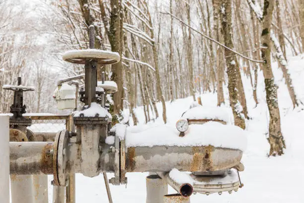 Photo of Gas pipes and valves in a snowy forest