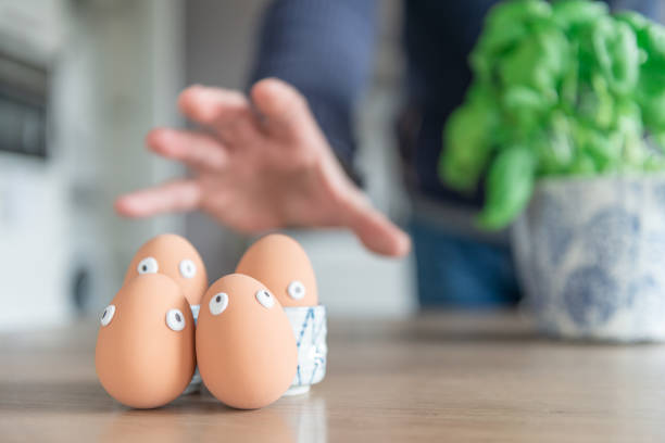 le uova di pasqua intasate si trovano durante la colazione di pasqua al tavolo della cucina, le uova vengono catturate da una mano di ragazzi. concetto di buona pasqua, tema pasquale, sfondo, cartolina, schermo, biglietto d'auguri, - breakfast easter yellow easter egg foto e immagini stock