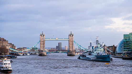 The historic HMS Belfast built for the Royal Navy, and now permanently moored as a museum ship on the River Thames in London. The Tower Bridge in background.