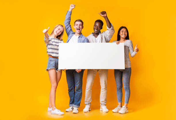 возбужденная группа подростков, держащих в руках пустой белый плакард - thumbs up teenager adolescence group of people стоковые фото и изображения