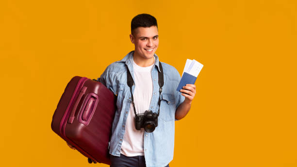 istock Smiling tourist with camera and suitcase holding ticket and passport 1210349969