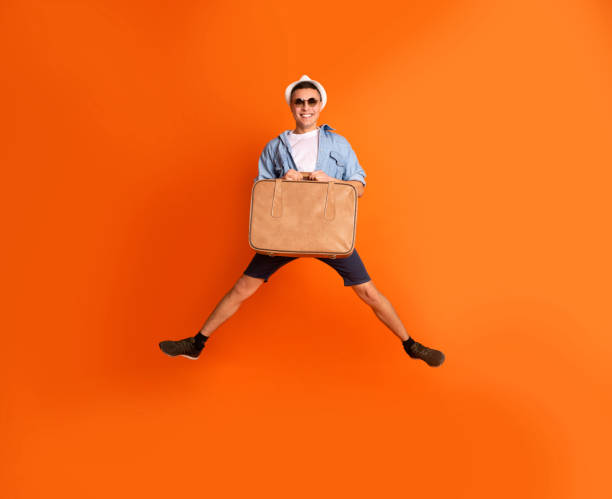 istock Excited tourist with suitcase jumping over orange background 1210350241