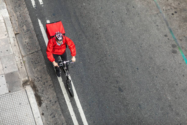 delivery man riding bicycle on city street on his way to customer - bicycle messenger imagens e fotografias de stock