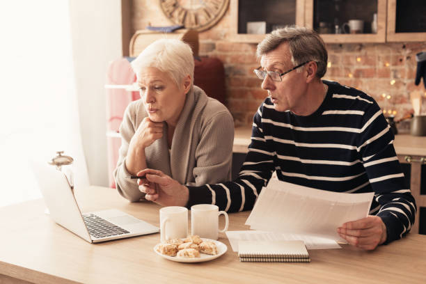 istock Worried Elderly Couple Using Laptop In Kitchen, Checking Domestic Finances 1210351175