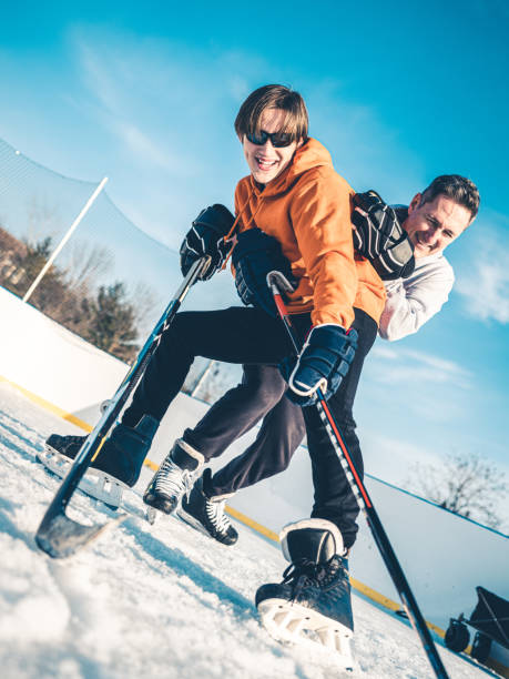 vater und sohn spielen hockey im freien - ice skating ice hockey child family stock-fotos und bilder