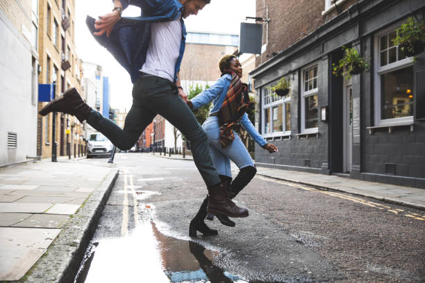istock Young couple jumping a puddle after the storm 1210351885