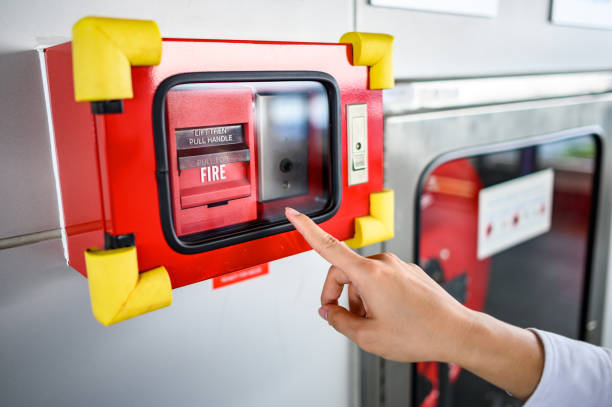 Male hand pointing at red fire alarm switch Male hand pointing at red fire alarm switch on concrete wall in office building. Industrial fire warning system equipment for emergency. emergency break glass box stock pictures, royalty-free photos & images