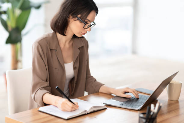 istock Portrait of manager using pc and writing in notebook 1210355839