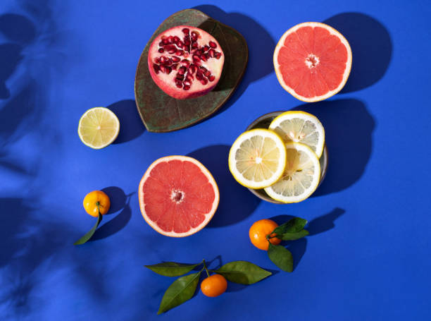 Composition with citrus fruits on a bright blue background. Bright light, contrasting shadows.