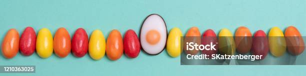 Little Yellow Red And Orange Easter Eggs Arranged Alternately In A Line Combined With An Easter Candy Designed As Egg White With Yolk On An Aqua Menthe Surface Stock Photo - Download Image Now