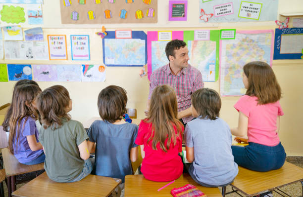 Teacher talking with a small group of children at school about values stock photo