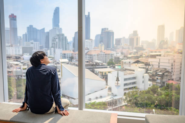 istock Asian man looking outside in office building 1210367550