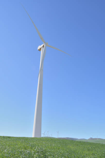 青空で晴れた日に移動する再生可能エネルギーの風力タービン - eolo ストックフォトと画像