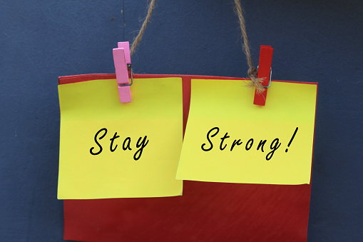 Inspirational quote - Stay strong. With origami paper notes hanging on wall. Encouragement concept with colorful creative papers.