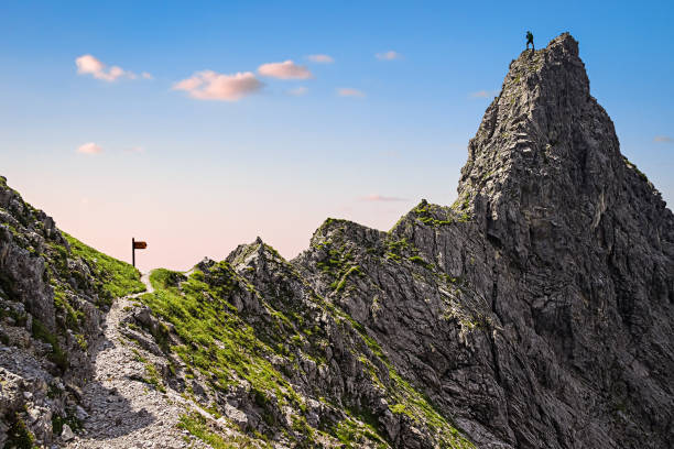 On Top of the Mountain One Single Climber on a Mountain Top and the Steep Path to the Summit steep photos stock pictures, royalty-free photos & images