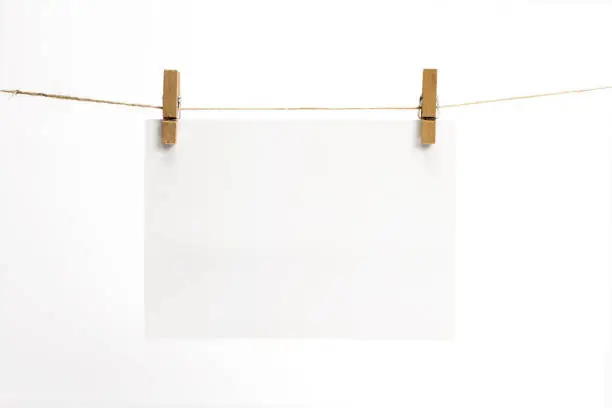 Photo of Empty paper sheets for note, frames that hang on a rope with clothespins and isolated on white. Blank cards on rope. Mockup template for memories backdrop, photos, social media etc.