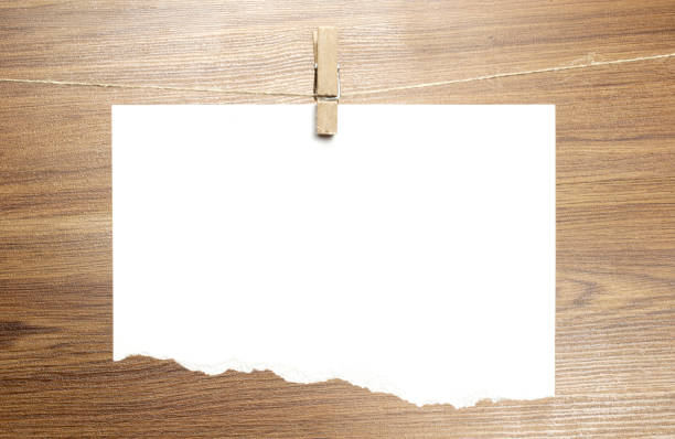 istock Empty torned paper sheet frame that hang on a rope with clothespins and on wooden background. Blank cards on rope. Mockup template for memories backdrop, photos, social media etc. 1210375142