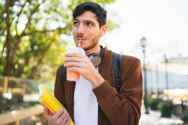 istock University student walking on the street while holding his books. 1210375227