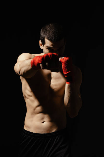 istock Athletic boxer punching with determination and precaution over black background 1210375863