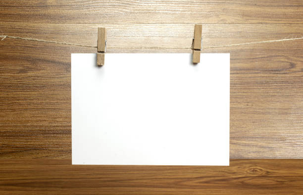 istock Empty paper sheet frame that hang on a rope with clothespins and on wooden background. Blank cards on rope. Mockup template for memories backdrop, photos, social media etc. 1210375889